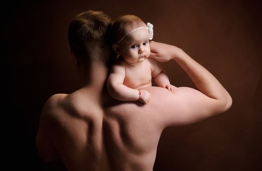 Male holding nice infant baby girl. Daughter on father's shoulders. Human growth and development. New generation. Cheerful man and his baby. New life concept. Dark background