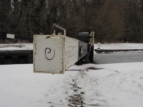 Lock gate in winter with snow on the ground and ice on the water, Padworth Lock, Kennet and Avon Canal, Berkshire, UK