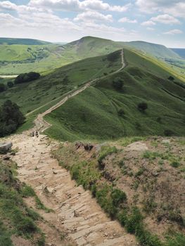 View walking down the steep rocky descent of Back Tor looking over to Mam Tor in the background, Peak District National Park, UK