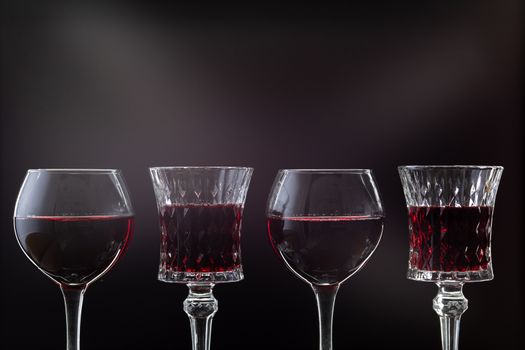 Rose wine. Red wine in four wine glasses over dark background with rays of light.