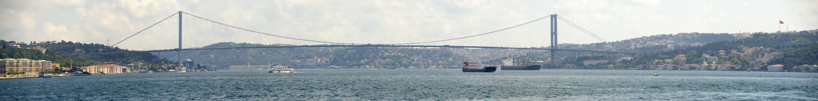 Panoramic view of Ataturk suspension bridge spanning the Bosphorus river in Istanbul, Turkey against a blue sky