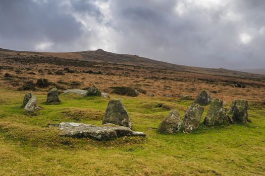 Nine Maidens Bronze Age megalithic cairn circle under Belstone Tor with dark brooding stormy sky, Dartmoor National Park, Devon, UK