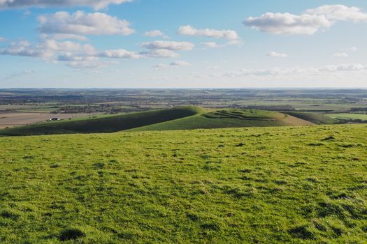 View from top of Tan Hill, the second highest point in Wiltshire, overlooking Cliffords Hill, the Vale of Pewsey and Salisbury Plain, with blue sky and white clouds, North Wessex Downs, UK