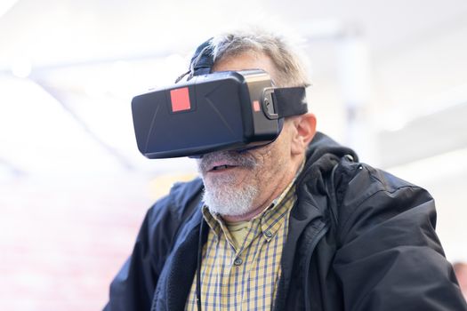 Senior man wearing virtual reality headset glasses. Virtual reality presentation.