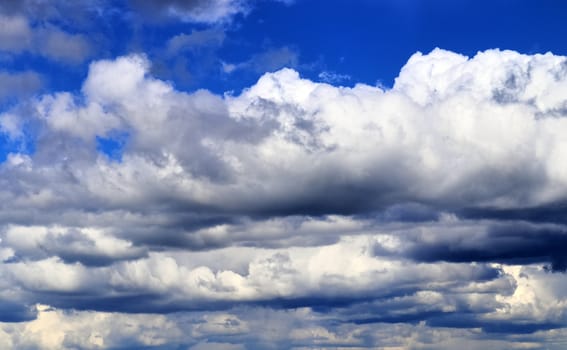 Beautiful fluffy white beautiful cloud formations in a deep blue summer sky