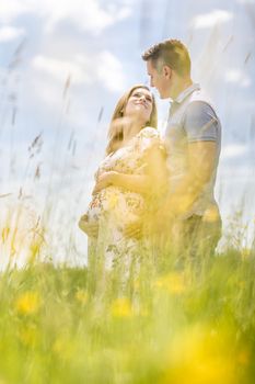 Young happy pregnant couple hugging in nature. Concept of love, relationship, care, marriage, family creation, pregnancy and parenting.
