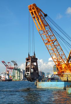 A clamshell dredger mounted on a barge in Kaohsiung port

