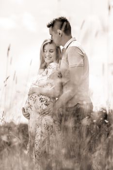 Young happy pregnant couple hugging in nature. Concept of love, relationship, care, marriage, family creation, pregnancy and parenting.