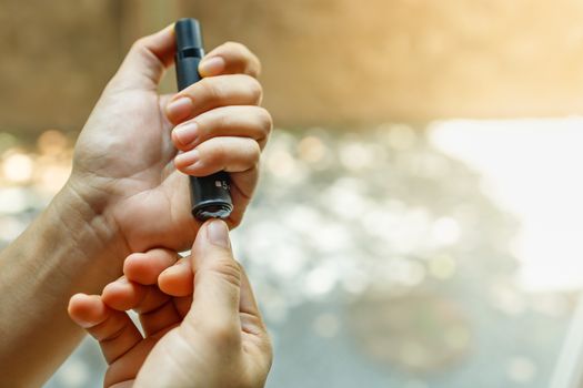 Close up of woman hands using lancet on finger to check blood sugar level by Glucose meter. Use as Medicine, diabetes, glycemia, health care and people concept.