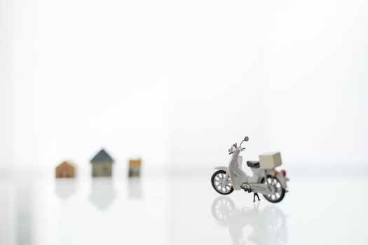 Stay home, Shelter in Place with Delivery and shopping online Concept. Close up of scotter / Motorcycle with container box and mini house as background.