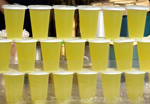 Plastic cups with juice stacked up at an outdoor stall
