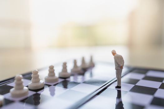 Business, Teamwork and Planning Concept.  Close up of businessman miniature people figure standing on chessboard with pawn chess pieces and copy space.