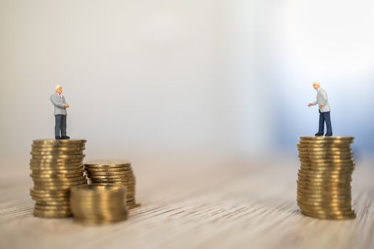 Business, Social Distancing Coronavirus, Covid-19 Protection Concept.  Two businessman miniature figure people standing on stack of gold coins on wooden table.