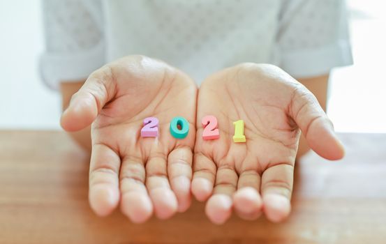 2021 New Year Planning and target Concept. Close up of colorful wooden number on woman hand on wooden table.