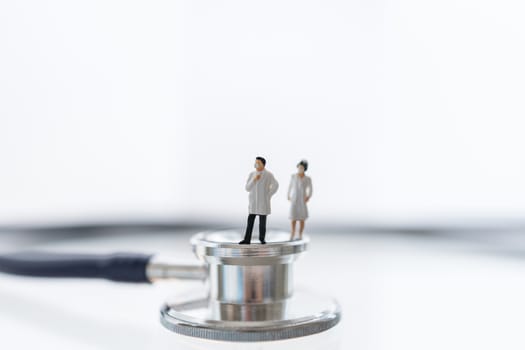 Global Healthcare, Coronavirus, Covid-19 Protection Concept. Doctor and nurse miniature figure people wearing surgical face mask standing on Stethoscope with white background.