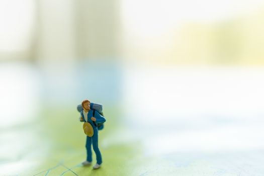 Travel concepts. Traveler miniature figures people with backpack standing on world map with copy space.