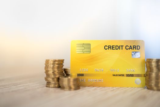 Business, Money, E-Commerce, Shopping Concept. Close up of mockup fake credit card with stack of gold coins on wooden table and copy space.