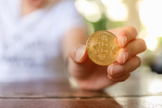 Business , Money, Technology and  cryptocurrency Concept. Close up of man hand holding gold bitcoin coins on wooden table.