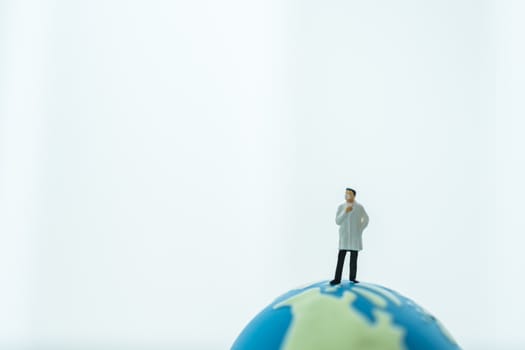 Global Healthcare, Coronavirus, Covid-19 Protection Concept. Doctor miniature figure people wearing surgical  face mask standing on mini world ball on white background and copy space.