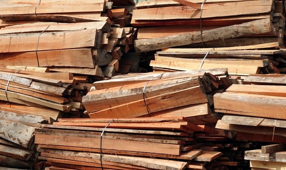 Large piles of hardwood lumber and planks are tied together with steel bands
