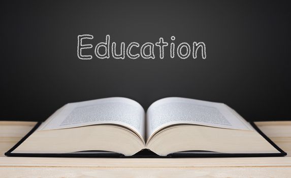 Book on blackboard background and light, education concept