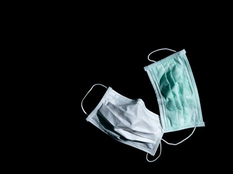 Used white and green surgical mask place on black background, Dark tone.