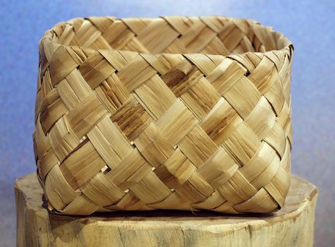 A handcrafted wicker basket sits on a tree stump