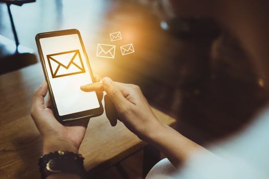 Woman hand using smartphone and it's show email recieve notification icon pop up on screen of mobile phone. Business communication  technology concept.