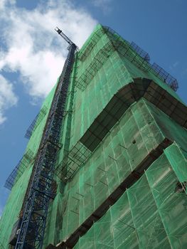 The massive frame of a modern building construction site with a crane attached on the building exterior 