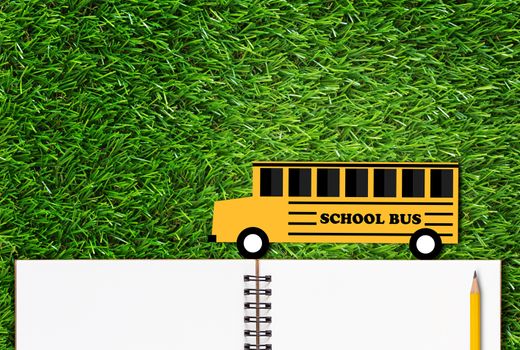 Education concept, knowledge management, back to school, paper cut yellow bus, pencil and open notebook on green grass background