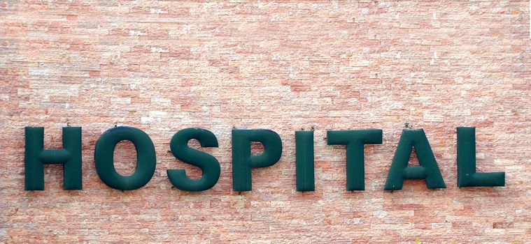The word Hospital is formed in big letters against a stone wall
