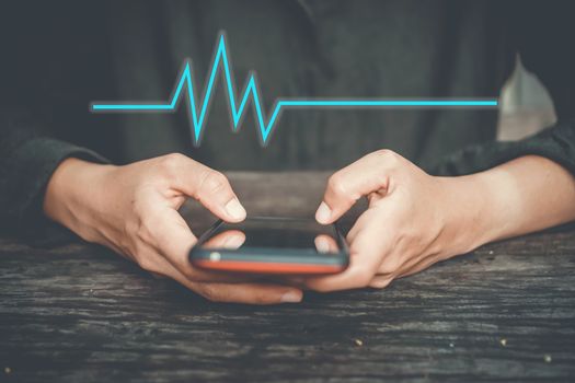 Woman hand holding smartphone with vital sign of heart beat background. Business technology health connection concept.