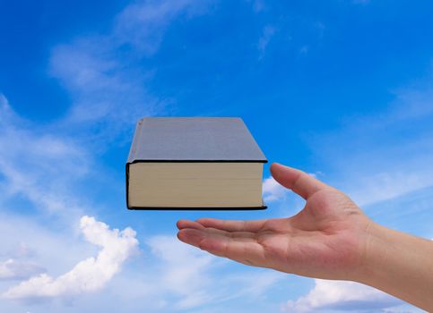 Knowledge management, education concept, hand and book on blue sky background