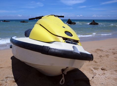 A jet ski sits on a nice beach with the blue ocean in the background

