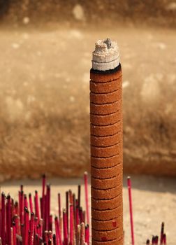 A large joss stick surrounded by smaller ones in a religious vessel
