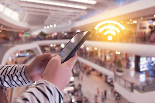 Woman hand using smartphone with wifi icon in public place outdoor background. Business communication social network concept.