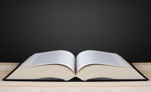 Book on blackboard background, copy space and light, education concept