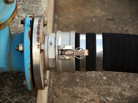 A thick fuel hose is connected to a blue steel pipeline
