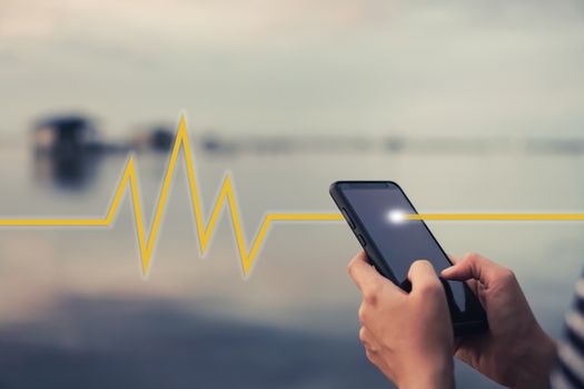 Woman hand holding smartphone with vital sign of heart beat background. Business technology health connection concept.