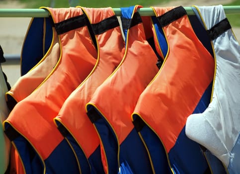 Bright red lifevests are hanging on a pole
