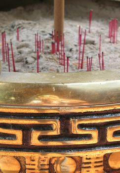 -- with red incense sticks placed amidst the ashes
