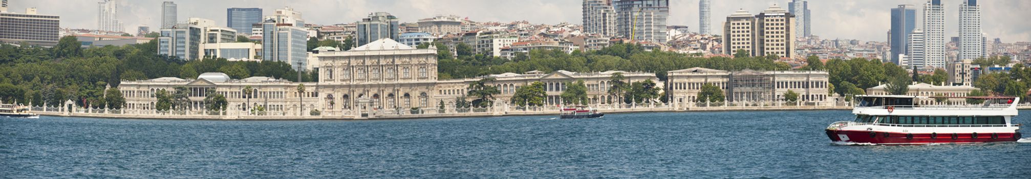 Panoramic view of Dolmabahce palace on bosphorus river in istanbul turkey with boat and cityscape in background