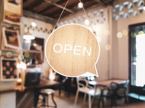 A business sign that says open on cafe or restaurant hang on door at entrance. Vintage color tone style.