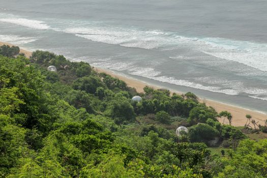 Bubble hotel at Nyang Nyang Beach on Bali Island, Indonesia. Romantic place ideal for honeymoon. A high reef off the coast of the Indian Ocean overgrown with dense tropical vegetation. Rainforest.