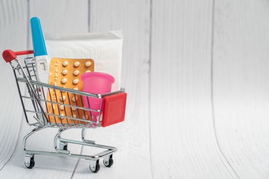 Pregnancy test, Birth control pill and sanitary napkin pad on Shopping cart. Concept for contraceptive.