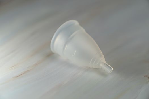 Menstrual cup on a white marble background.