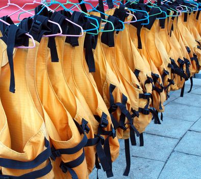 Orange life vests are drying on clothes hangers
