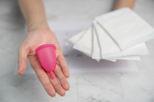 The choice between menstrual cup and sanitary napkin on woman hand.