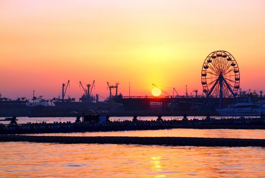 View of Kaohsiung Harbor at sunset with the silhouette of a small ferris wheel
