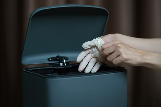 Hand putting used dirty surgical glove to a garbage bin. Mask protect dust and corona virus in trash.